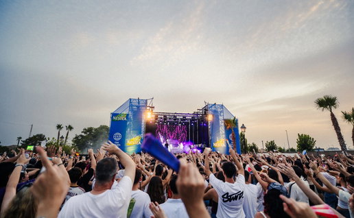 A large crowd at a festival in front of a stage
