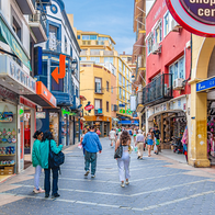 Tourists walking past local shops in central Benidorm during summer.