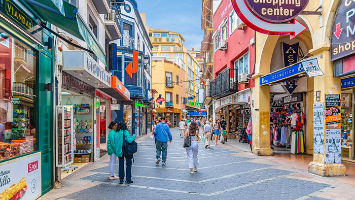 Tourists walking past local shops in central Benidorm during summer.