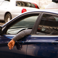 Man hangs his arm out of the car window while driving
