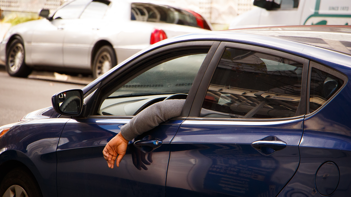 Man hangs his arm out of the car window while driving