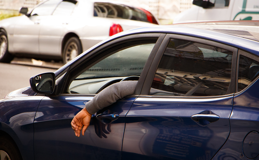 Man hangs his arm out of the car window while driving