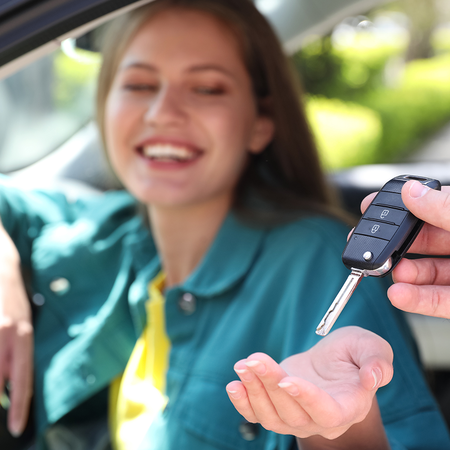 Woman sat in a car being handed the car keys.