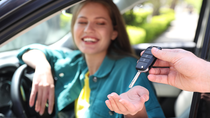 Woman sat in a car being handed the car keys.
