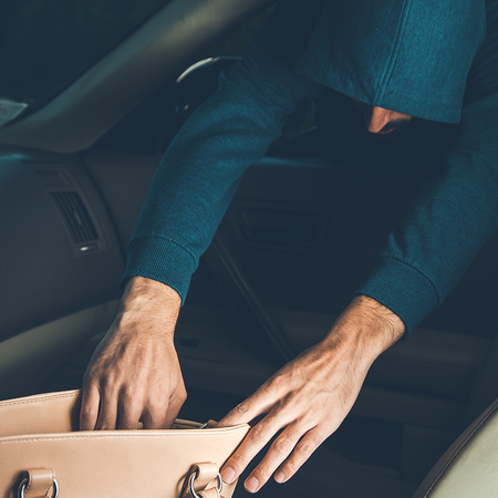 Thief reaches into car to take a bag.