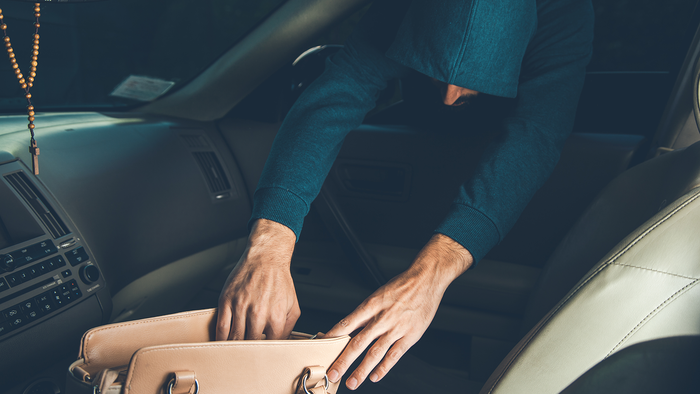 Thief reaches into car to take a bag.