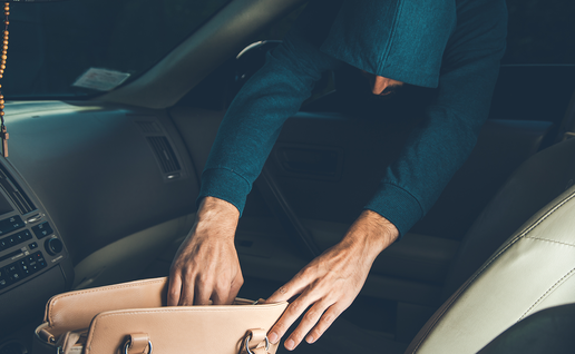 Thief reaches into car to take a bag.