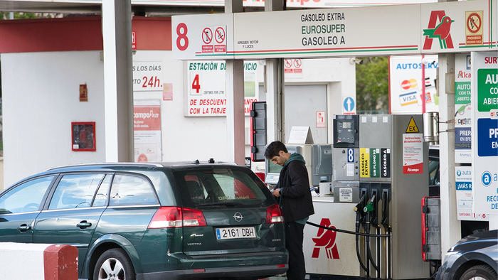 Driver filling a car at a petrol station beside a Spanish motorway during a summer journey.