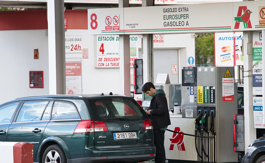 Driver filling a car at a petrol station beside a Spanish motorway during a summer journey.