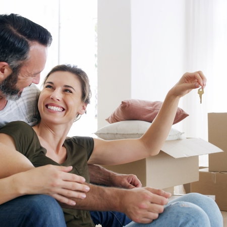 Boxes, couple or excited with key in new home for property purchase, real estate or growth. Moving, man or hug woman with keychain for investment, relocation pride or security deposit success