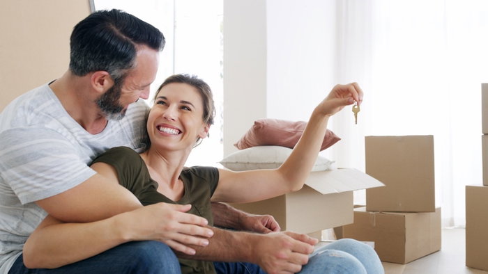 Boxes, couple or excited with key in new home for property purchase, real estate or growth. Moving, man or hug woman with keychain for investment, relocation pride or security deposit success