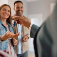Close up of happy couple receiving keys of their new home in Spain from real estate agent.