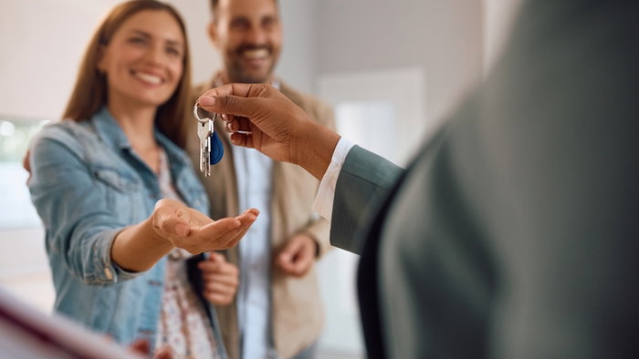 Close up of happy couple receiving keys of their new home in Spain from real estate agent.