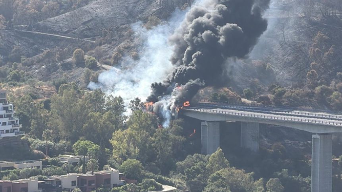 Flames and black smoke rise from a burning fuel tanker on an AP-7 bridge near Benahavís and Estepona.
