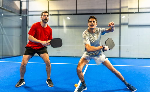 2 active men playing a pickleball match