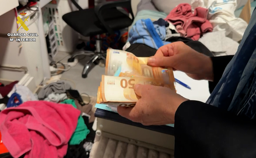 A person counts €50 banknotes in a room during the Guardia Civil investigation.