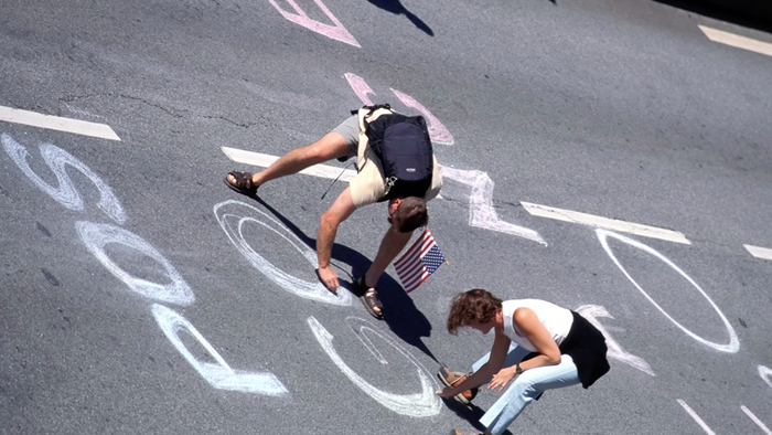 People drawing on asphalt.