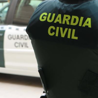 Guardia civil officer standing next to a Guardia Civil vehicle.