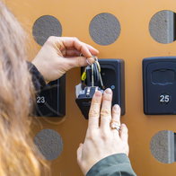 Property owner placing a key in a self check-in lockbox outside a holiday rental apartment in Spain.