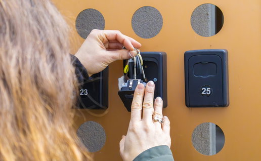 Property owner placing a key in a self check-in lockbox outside a holiday rental apartment in Spain.