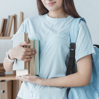 Young girl student holding her books with a blue backpack on