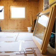 Worker in the backgournd in a Wooden house installing wooden windows for sustainable living & energy savings