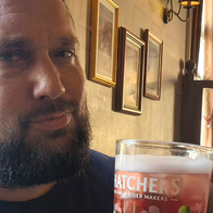 Dale Harvey sitting inside a British pub with a glass of cider.