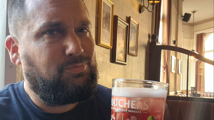 Dale Harvey sitting inside a British pub with a glass of cider.