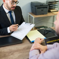 An immigration lawyer discusses a residence application with foreign clients during a consultation on family reunification and immigration procedures.