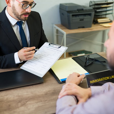 An immigration lawyer discusses a residence application with foreign clients during a consultation on family reunification and immigration procedures.