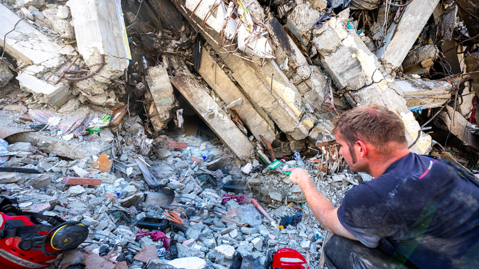 Rescue team members inspect a damaged building while searching for survivors