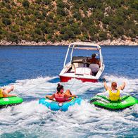 Friends having fun, riding on water tube during summer vacation