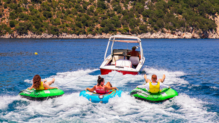 Friends having fun, riding on water tube during summer vacation