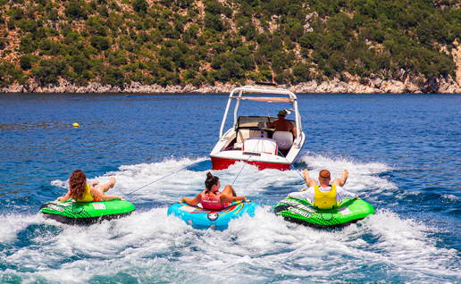 Friends having fun, riding on water tube during summer vacation