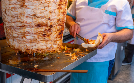 A man cutting kebab meat in a shop