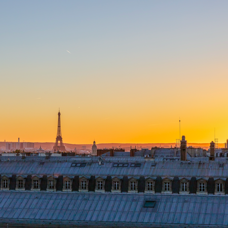 View of Paris at sunset with the Eiffel tower visible over the rooftops