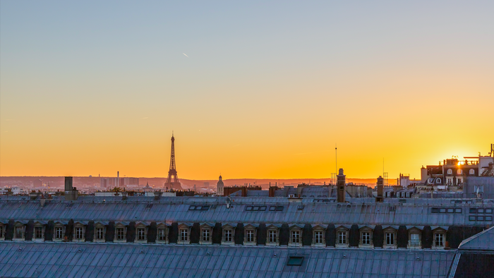 View of Paris at sunset with the Eiffel tower visible over the rooftops