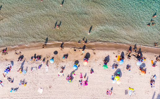 Aerial view of sandy beach with tourists swimming in beautiful clear sea water