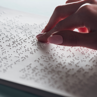 cropped view of young woman reading braille text on white paper
