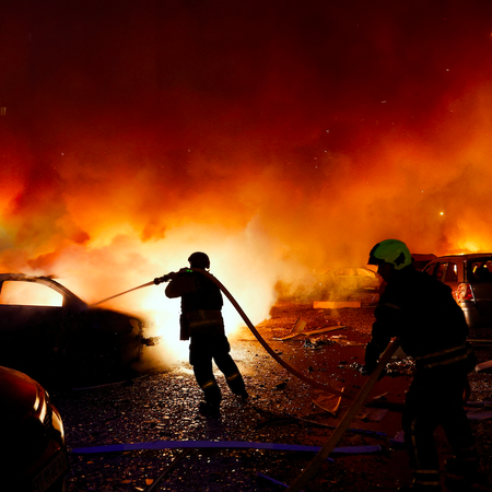 Firefighters trying to put out burning cars from a forest fire