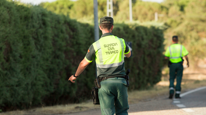 A Guardia Civil officer puts his hand out to pull a car over to the side of the road
