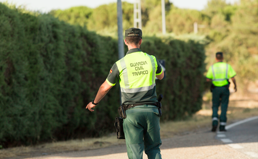 A Guardia Civil officer puts his hand out to pull a car over to the side of the road
