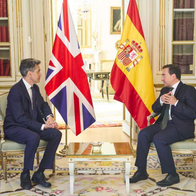 Spanish and UK foreign Ministers sitting down during a meeting in Madrid with both Spanish and UK flags in the backgrounds