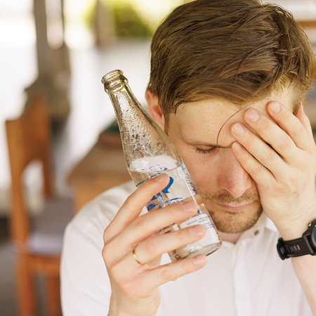 Man holds cold bottle up to face during heat.