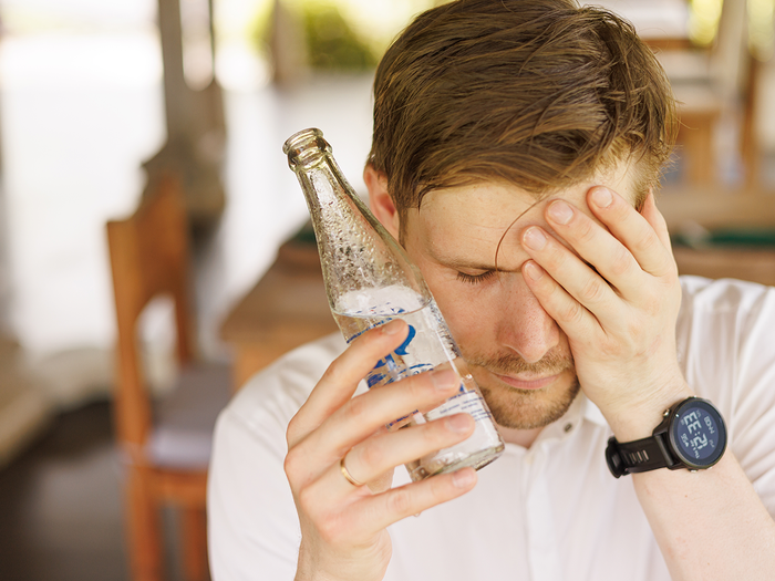 Man holds cold bottle up to face during heat.