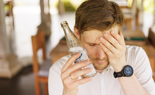 Man holds cold bottle up to face during heat.