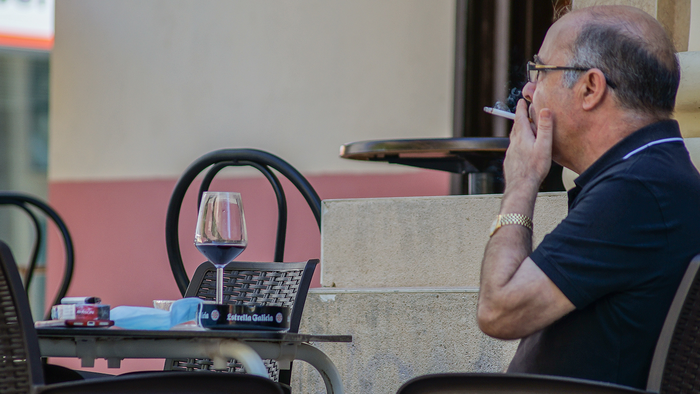 Customer smoking on an outdoor bar terrace in Spain.