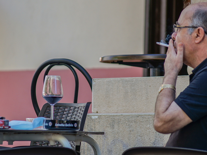Customer smoking on an outdoor bar terrace in Spain.