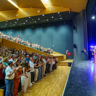 Audience members standing and applauding across the stalls and balcony inside the Auditorio Ciudad de Vera.