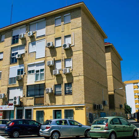 Apartment building in Spain with multiple outdoor air conditioning units mounted on the façade.